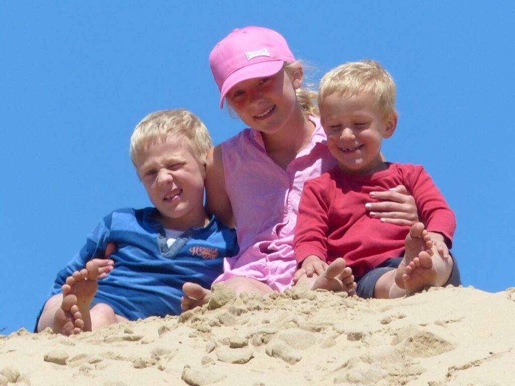 A girl and two boys on a dune, all three of whom have Fragile X