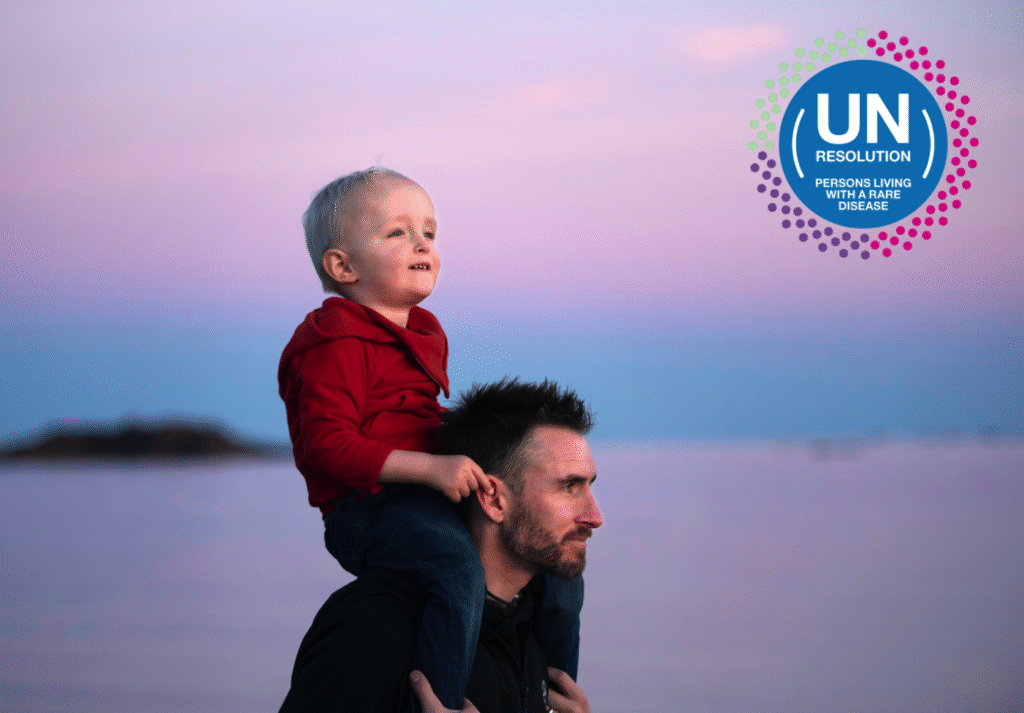 Man with a boy on his shoulders confidently walking in the sunset