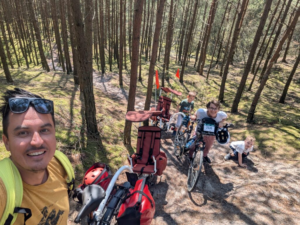 Family in the woods with 2 bikes and 2 trailers for the boys to padel