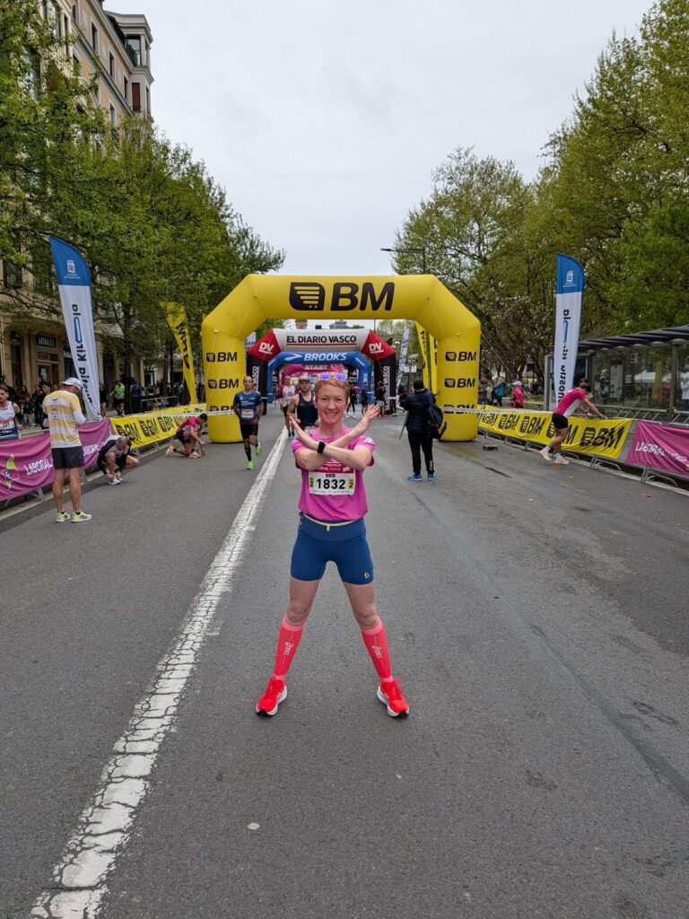 Brid posing for the camera before running a marathon, forming an X with her arms