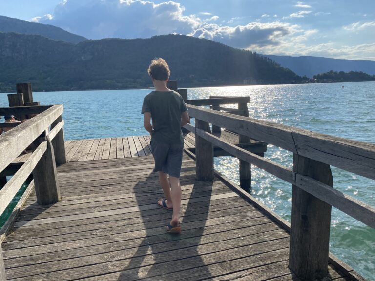 A boy walks away from the photographer at a lake.